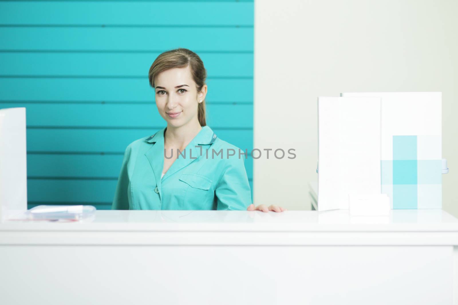 Female doctor or nurse in medical uniform looking straight. A hospital reception by selinsmo