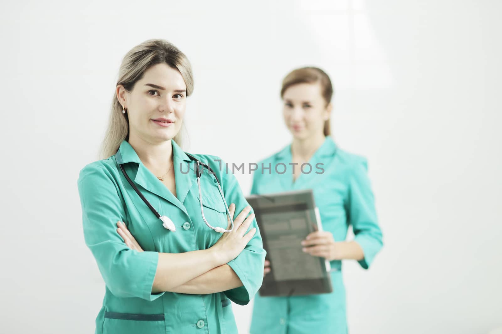 Two female doctors or nurses looking at the camera. Stethoscope on the neck by selinsmo