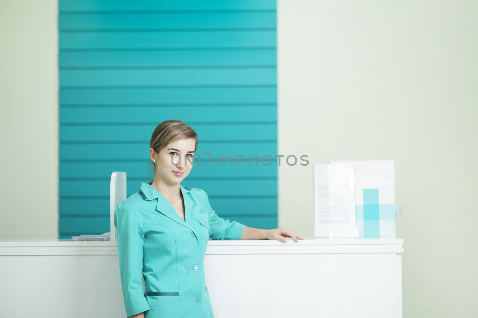 Female doctor or nurse in medical uniform looking at the camera. In the hospital reception.