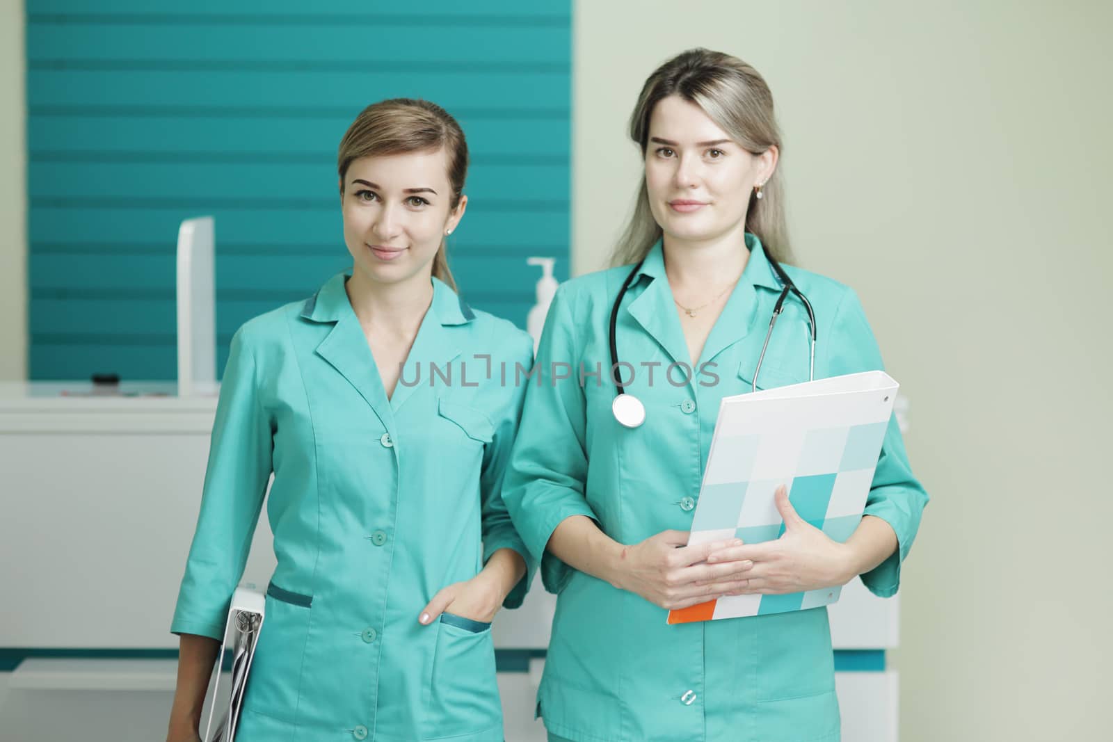 Two female doctors or nurses looking at the camera. Stethoscope phonendoscope on the neck. Holds a folder in his hands