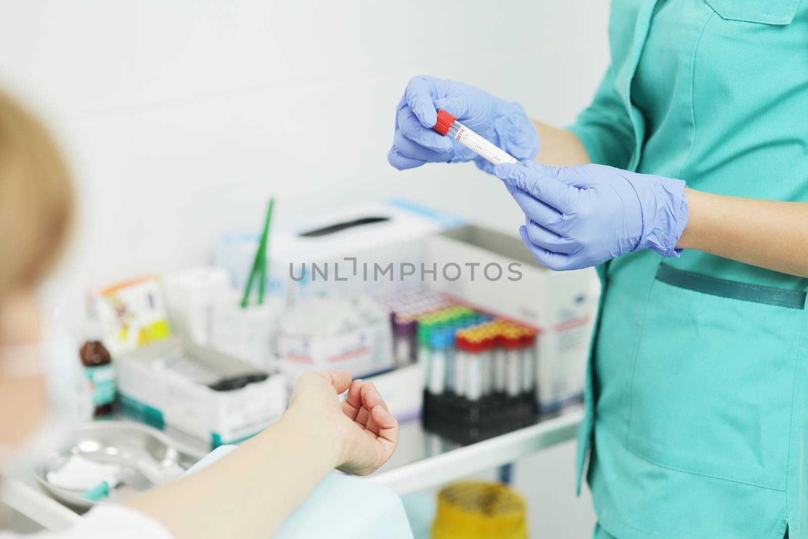 Woman nurse doctor in a medical mask holds a test tube for a blood test