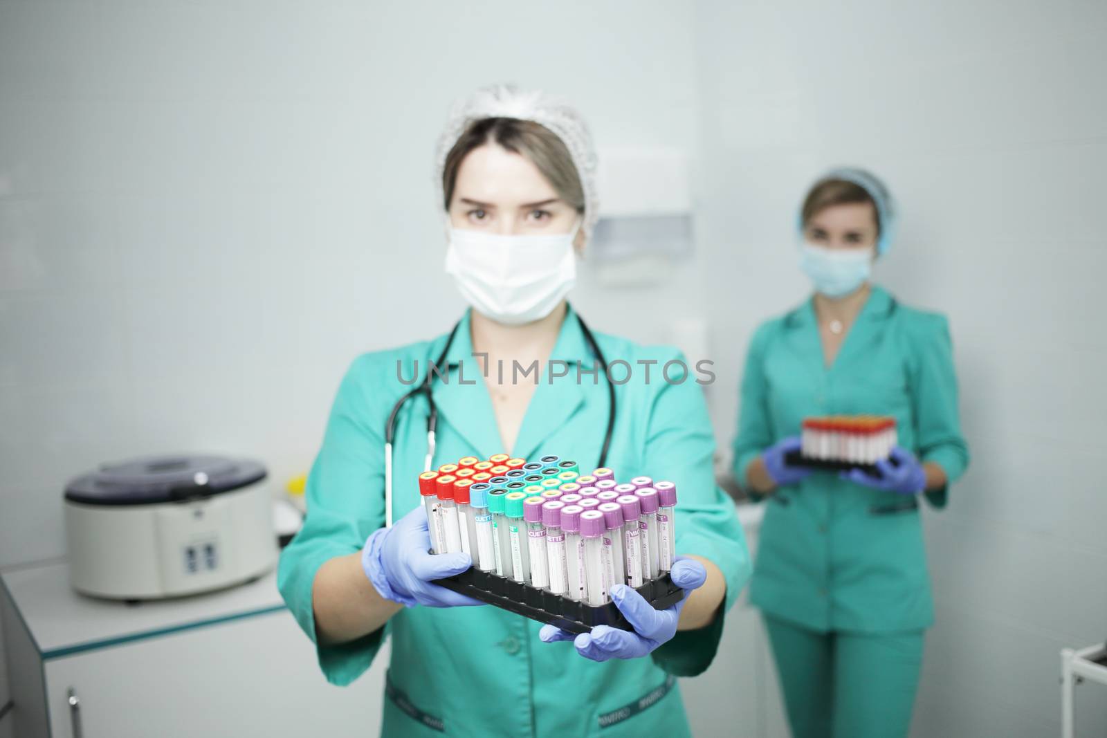 Two female nurses doctor in a hospital in a medical mask and medical clothes hold cones of a test tube for a blood test