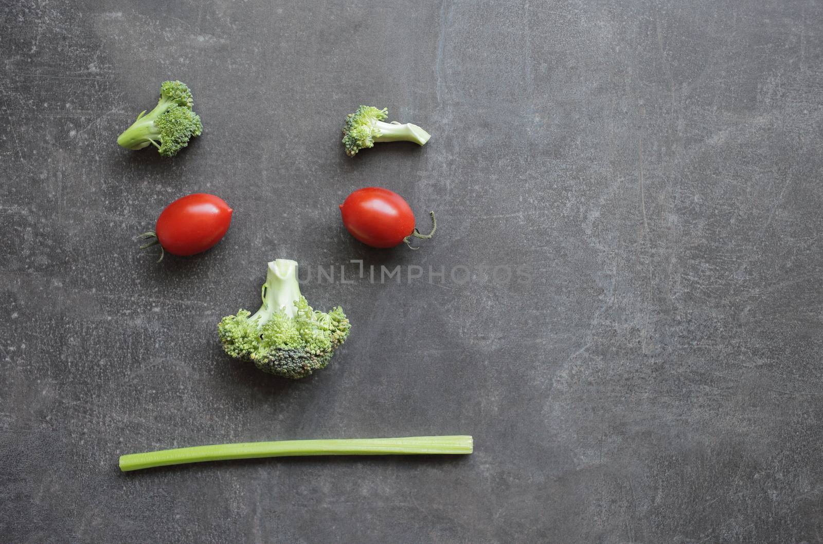 Displeased emoticon of fresh vegetables cherry tomatoes broccoli and celery. High quality photo