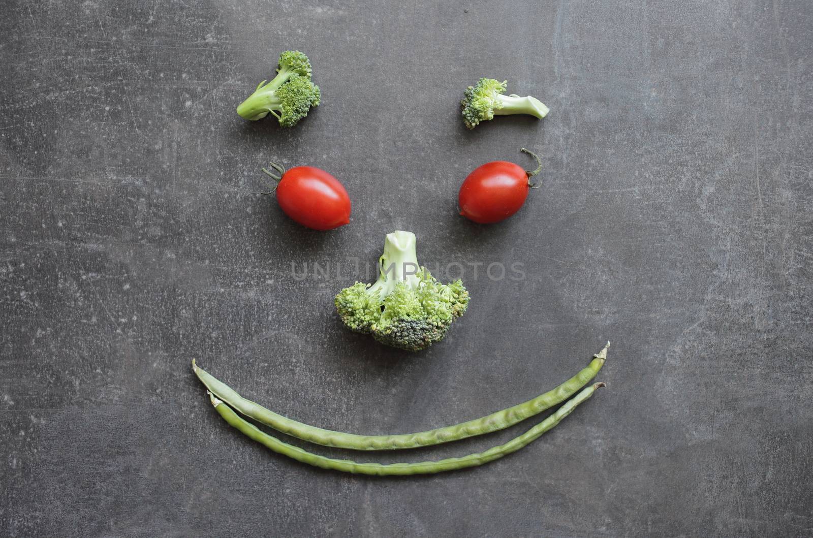 Smiling emoticon of fresh vegetables cherry tomatoes broccoli and green beans. High quality photo