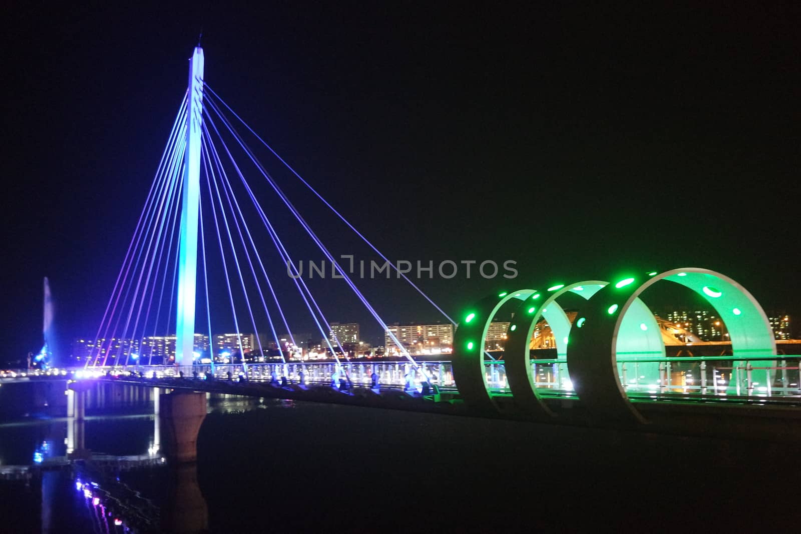 Night view of a beautiful scene of bridge over sea water in the evening time with colorful lights.