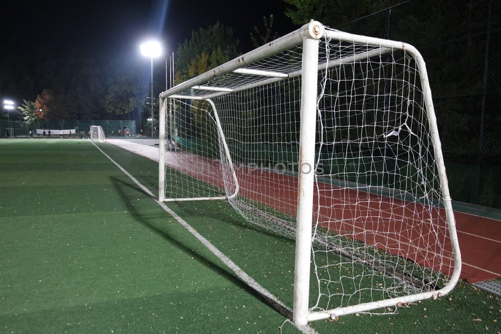 Night view of a soccer goal net under flood lights. Closeup view of goal net in a soccer playground