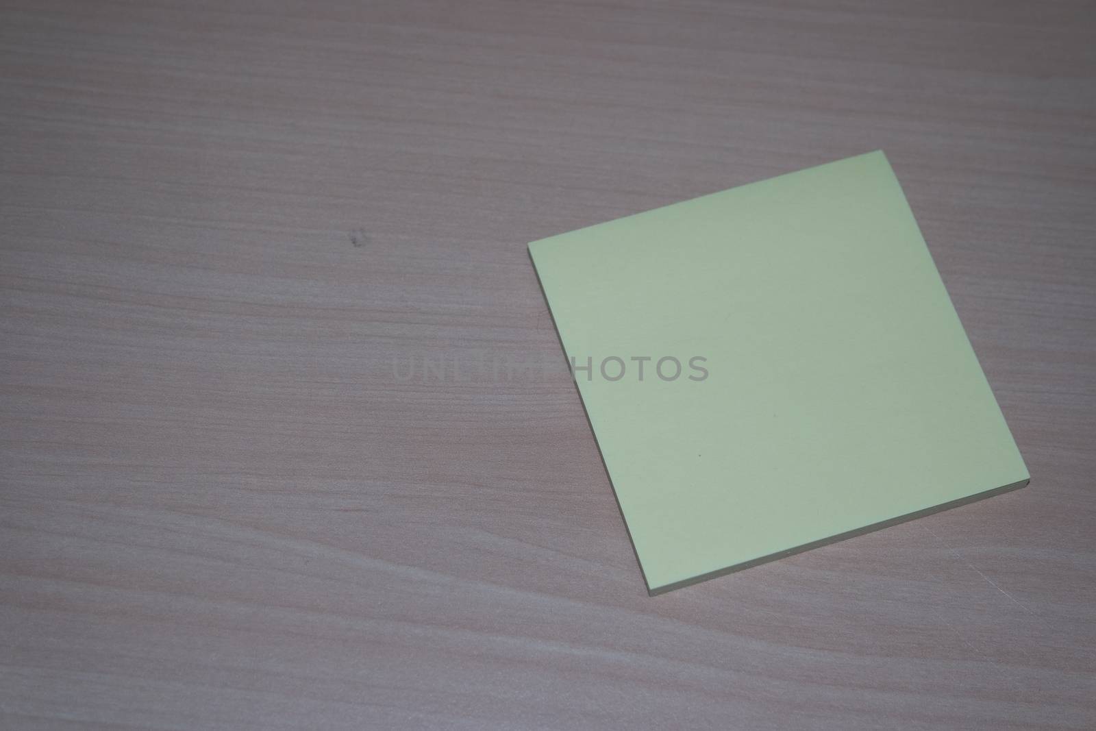 Close-up, selective focus: Yellow sticky note paper placed on a wooden table with copy space for text