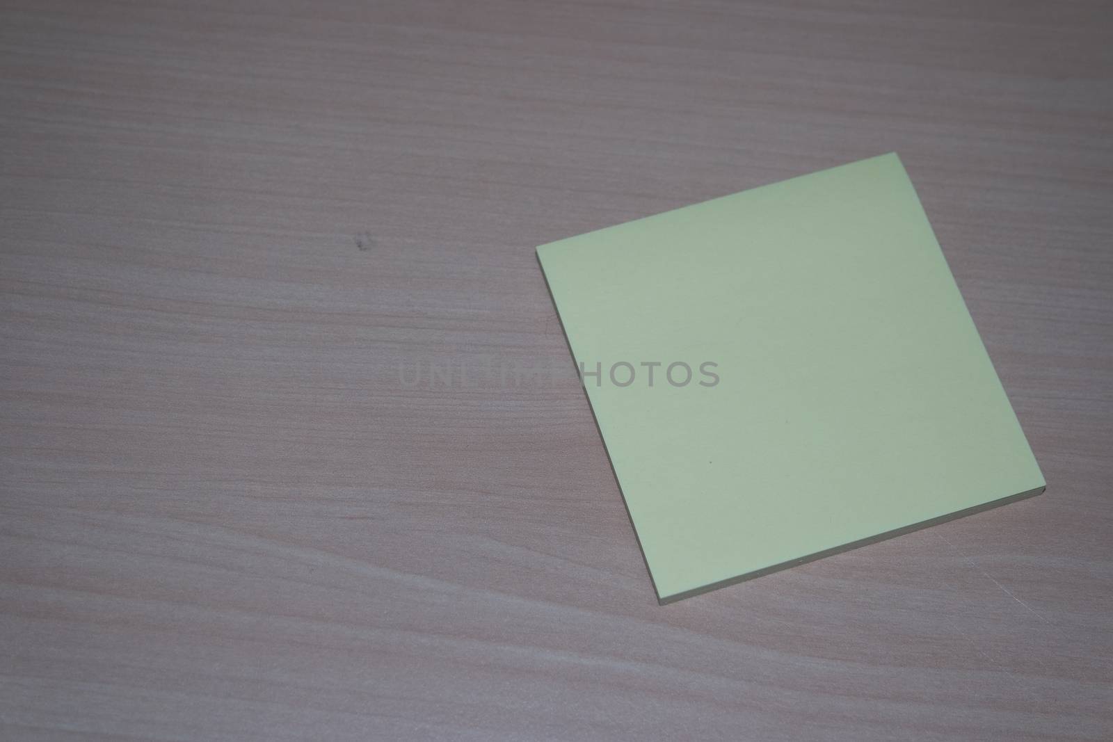 Yellow sticky note paper placed on a wooden table by Photochowk