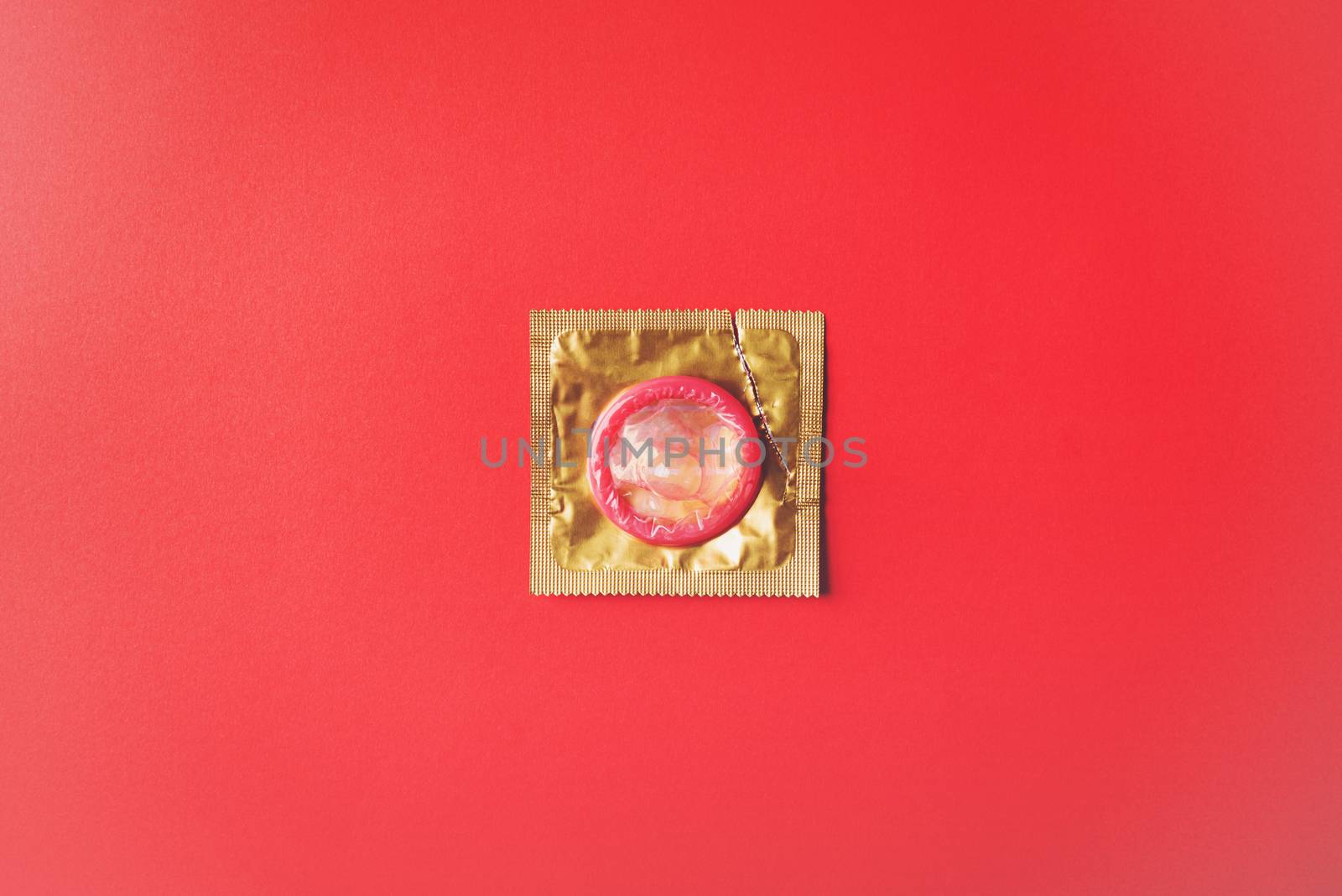 World sexual health or Aids day, Top view flat lay condom in wrapper pack is tear open, studio shot isolated on a red background, Safe sex and reproductive health concept