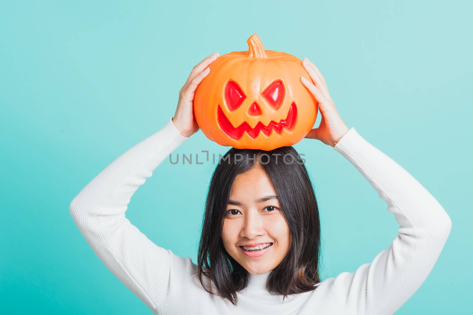 woman holding orange model pumpkins and put it on the head by Sorapop