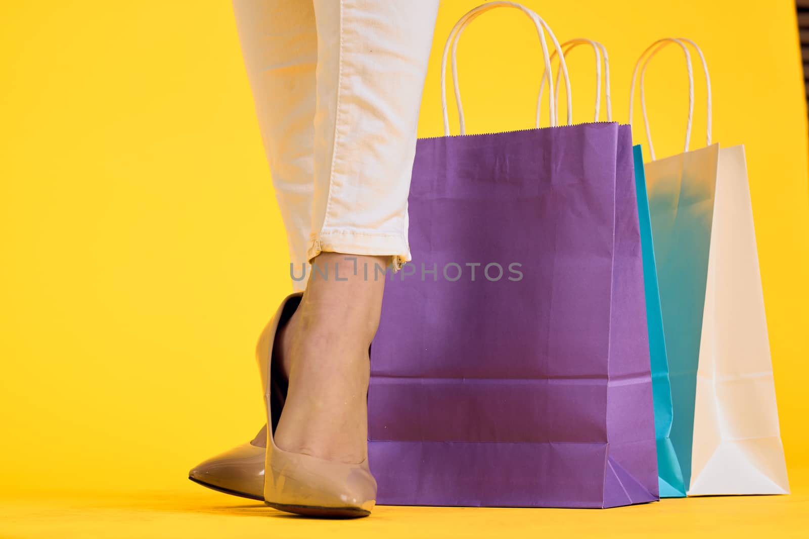 female feet in shoes packs shopping lifestyle yellow isolated background. High quality photo