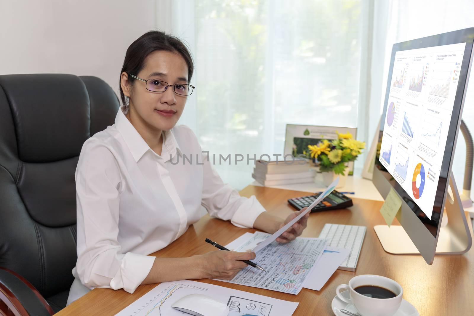 Business women smileing  wear glasses hands holding paper and pencil. business people analysis chart data on computer PC screen at office. Business at home concept.