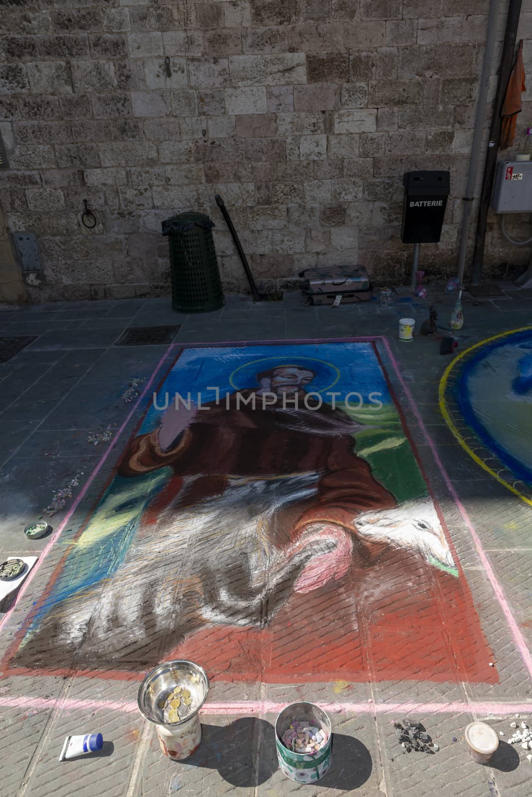 gubbio,italy august 29 2020:street artist and his works drawn on the ground