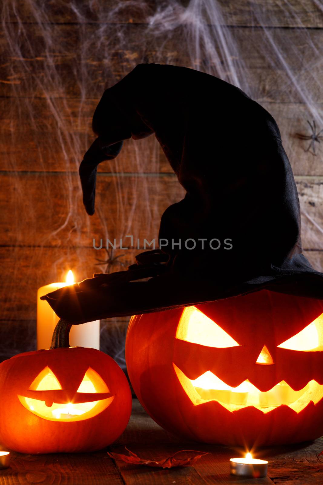 Jack O Lantern Halloween pumpkin with witches hat , spiders on web and burning candles