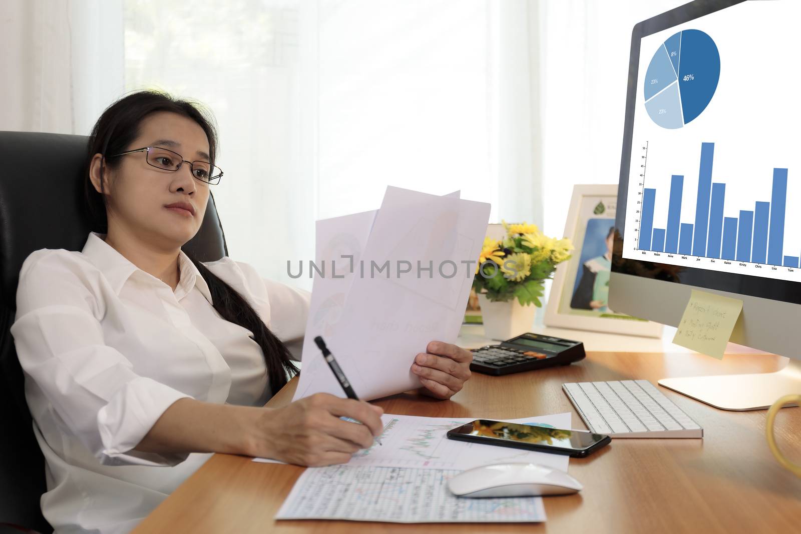 Business woman working in office with computer holding chart report paper and looking. business people working at home with paper and PC screen. Business and finance ,work at home concept