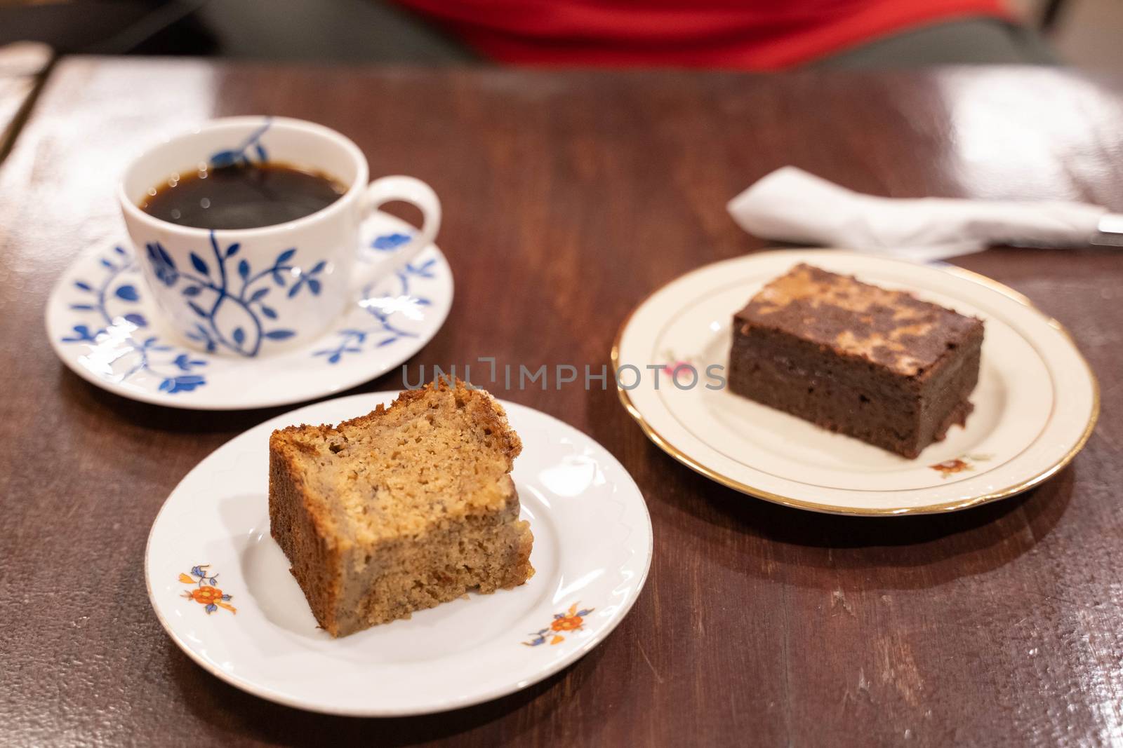 Two slices of cake and cup of coffee on wooden table by uphotopia