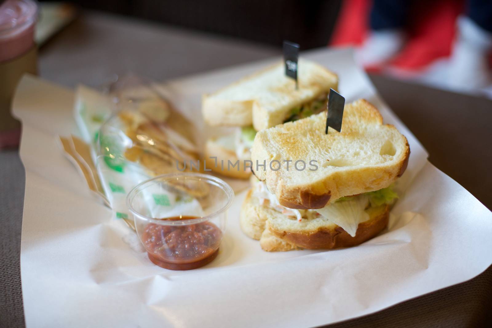 Two slices of sandwich and sauce on white paper by uphotopia