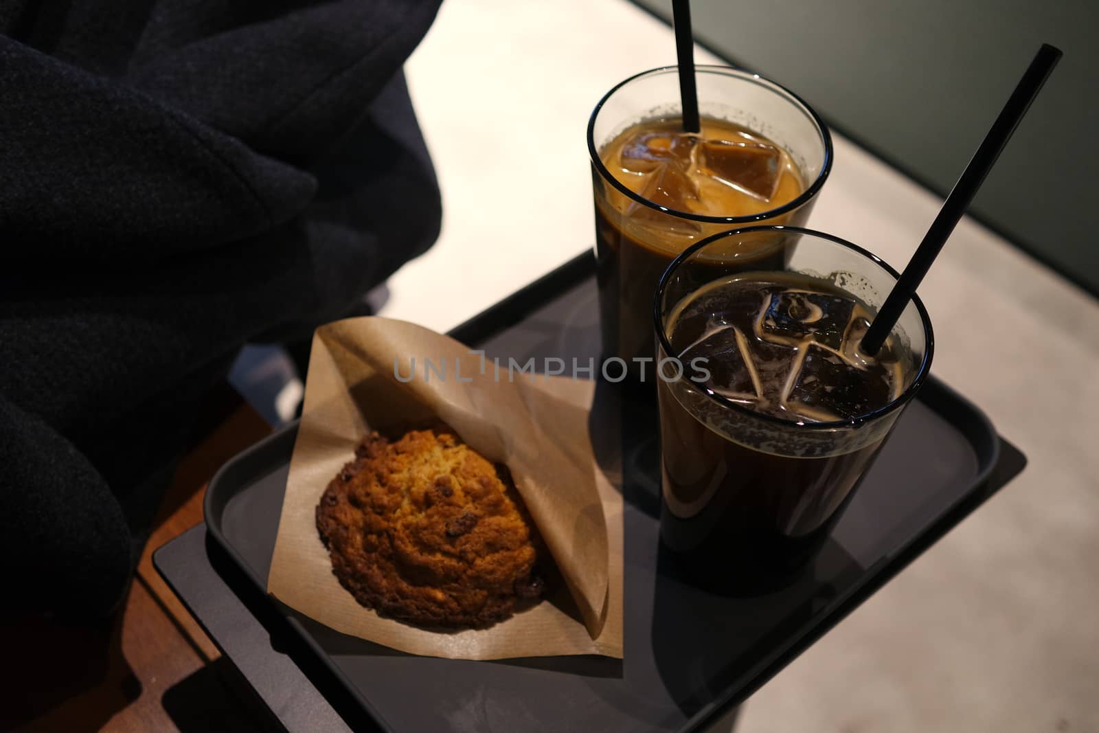 Bread and two cup of iced coffee on black tray by uphotopia