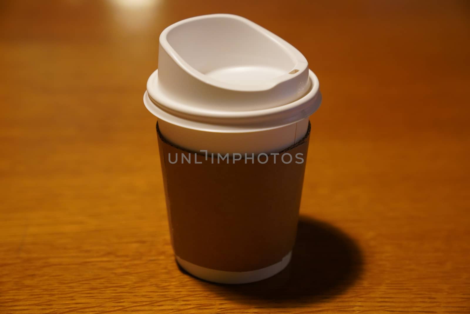 Cup of coffee with paper cup holder on wooden background