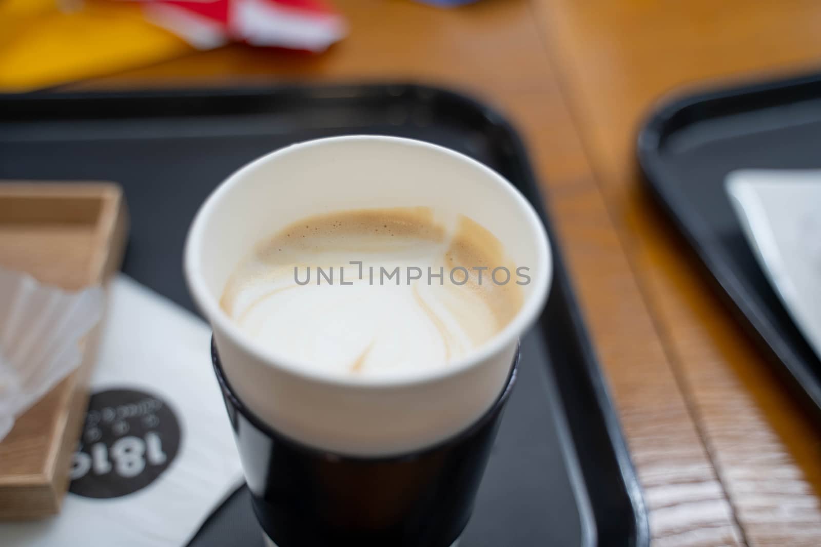 Cup of coffee with paper cup holder on wooden table by uphotopia