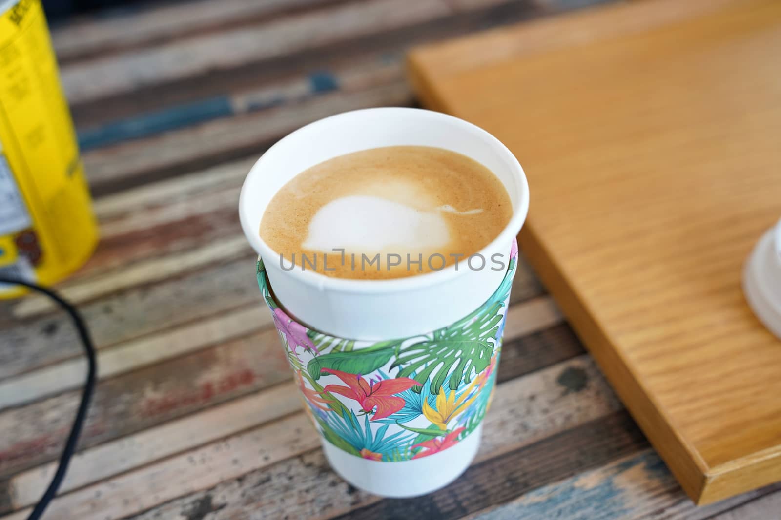 Cup of coffee with paper cup holder on wooden table by uphotopia