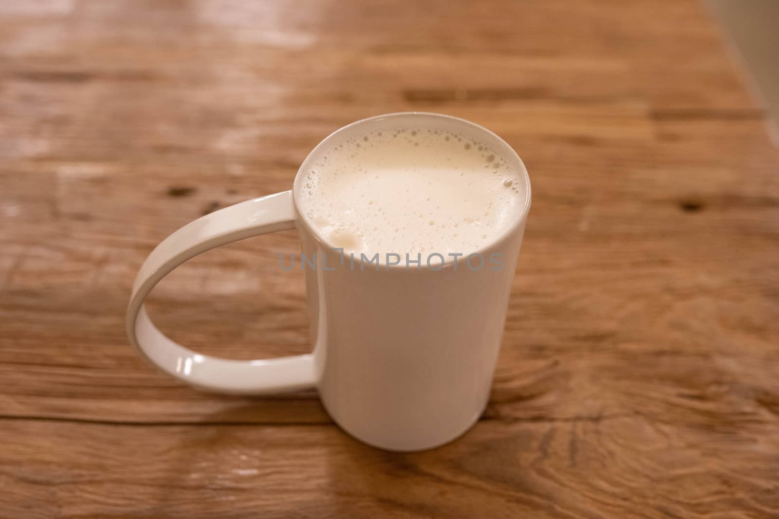 Cup of steamed milk on wooden background by uphotopia