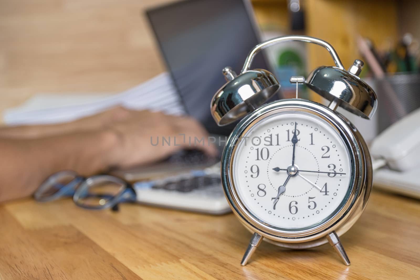 clock on work desk  in the work office Time of working concepts office life on morning, selective focus the clock