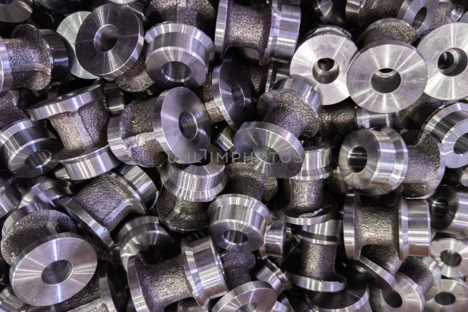 abstract close-up full frame dark industrial backdrop of forged and turned small steel spool-like parts