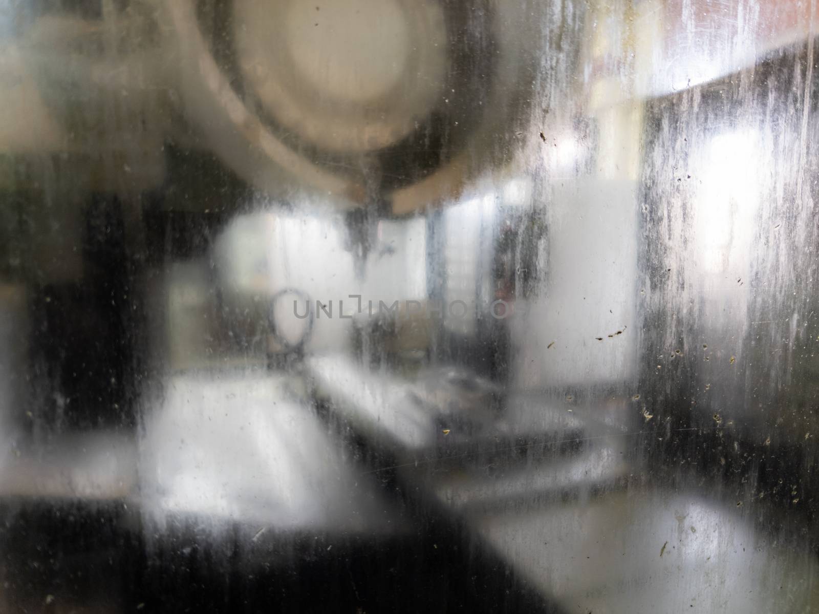 wet and dirty protective glass of cnc milling machine - close-up with selective focus and blur