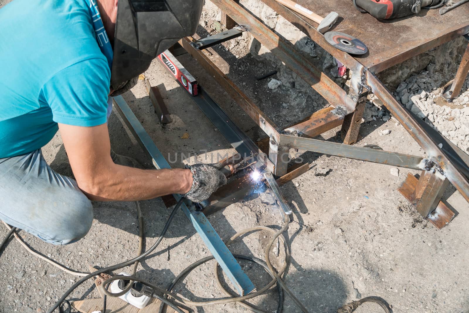 Welder welds metal structure. Construction worker at work. A working welder builds or repairs a new porch and facade of a building or structure. Construction and repair work on the street outdoor.