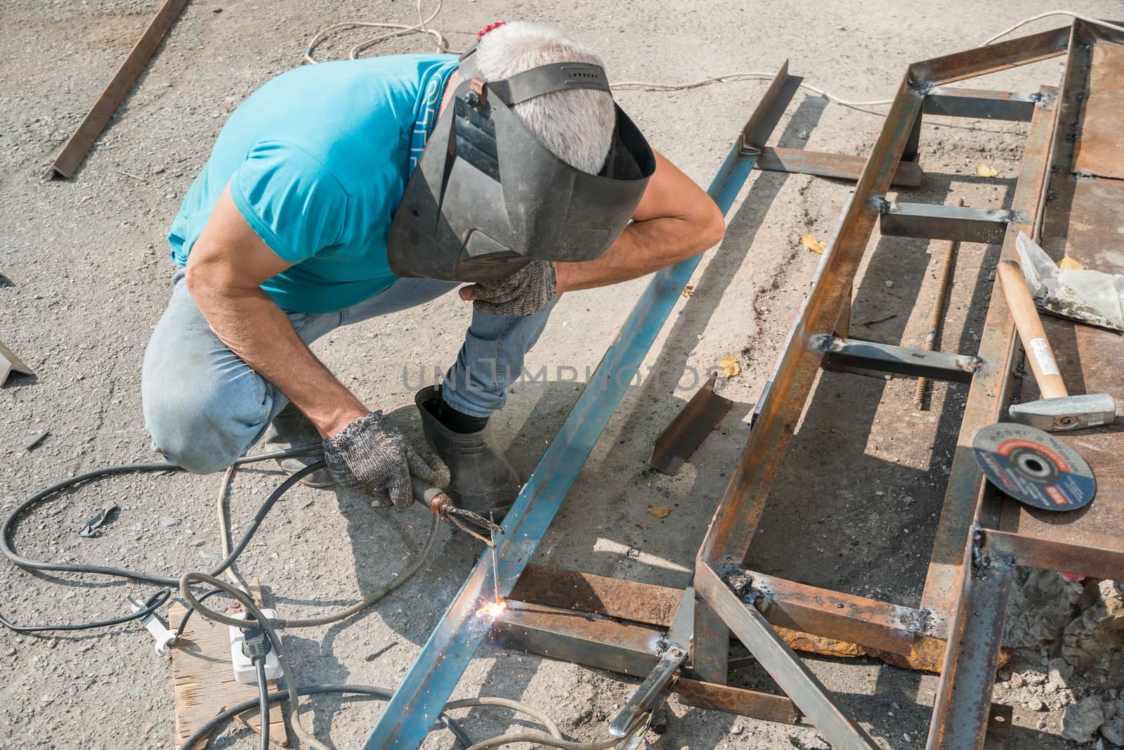 Welder welds metal structure. Construction worker at work. A working welder builds or repairs a new porch and facade of a building or structure. Construction and repair work on the street outdoor.