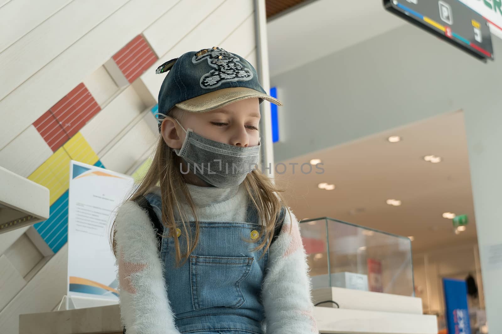 Baby girl with sad eyes in a protective medical mask at the airp by YevgeniySam