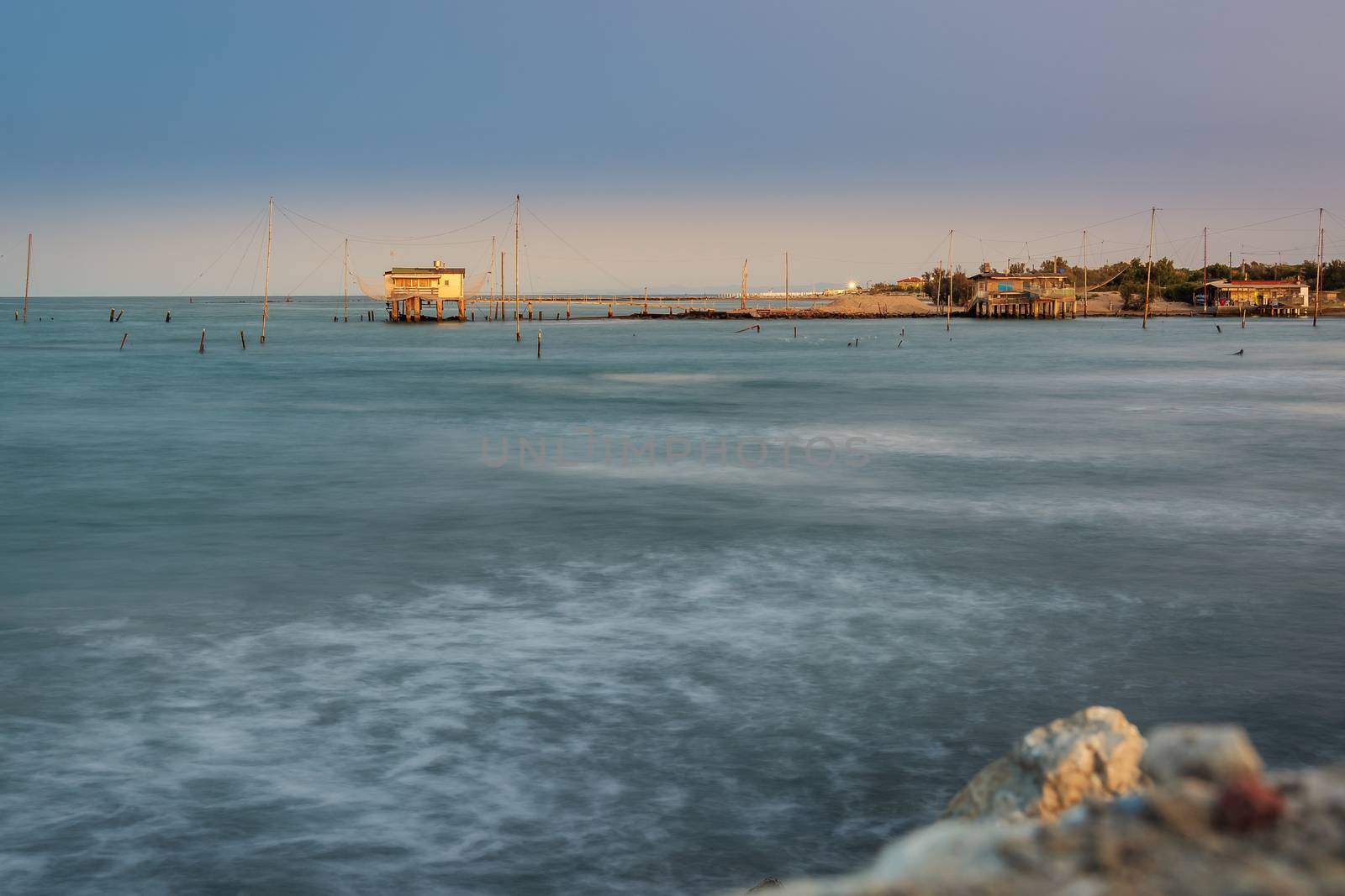 Fishing huts with typical italian fishing machine called "trabucco",at wonderful sunset ,long exposure photo,Lido di Dante, fiumi uniti Ravenna near Comacchio valley.