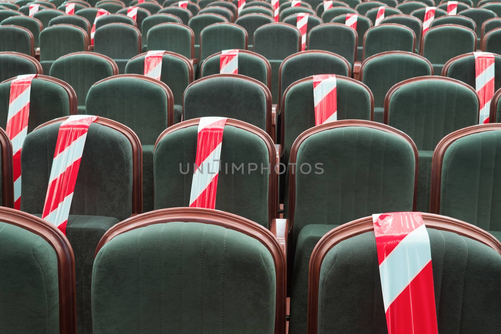 Need to sit on a chair separated by a ribbon in the cinema, theater, auditorium. Maintaining a safe social distance in public places, gatherings of people, events. Warning mark on the seats by synel