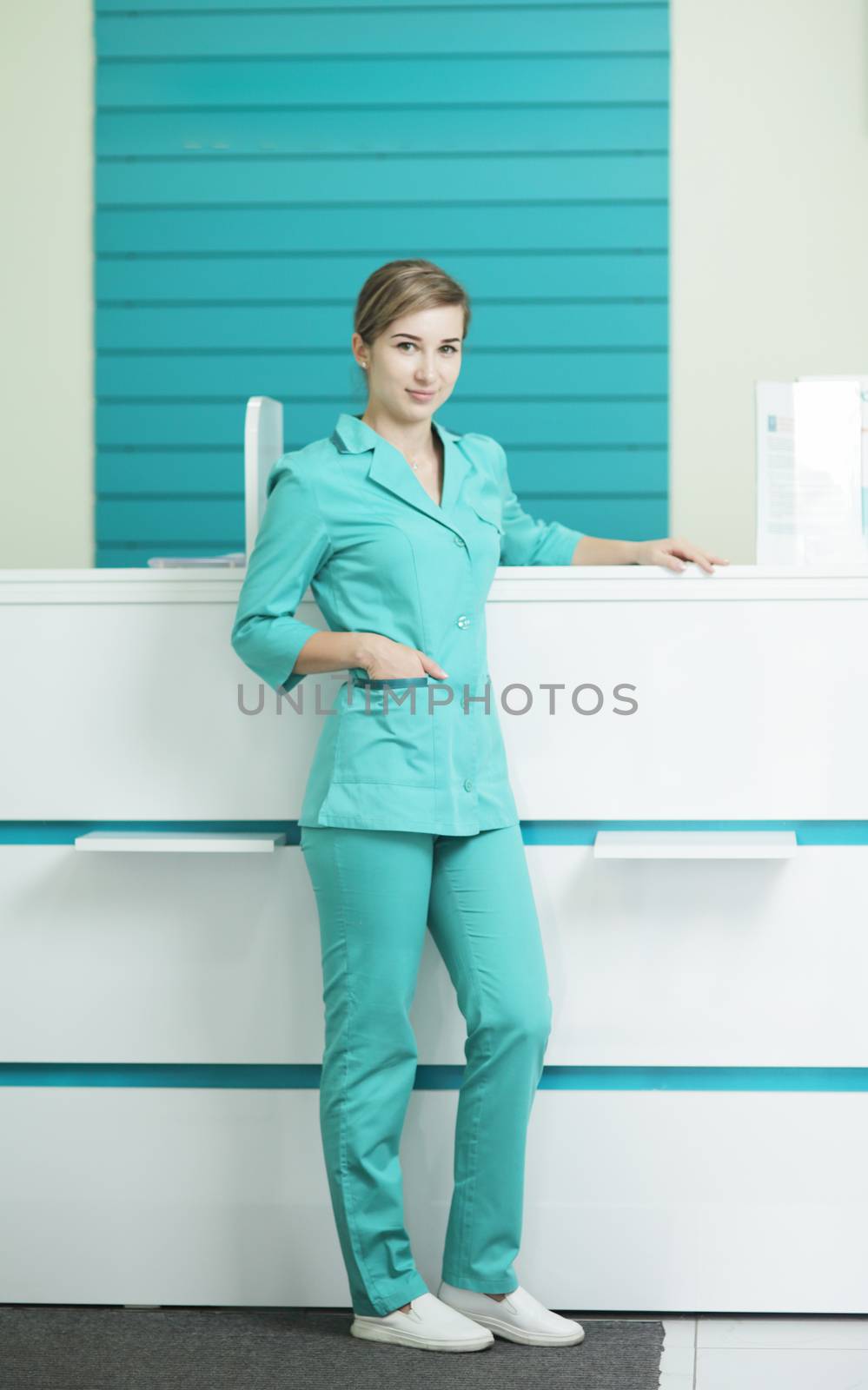 Female doctor or nurse in medical uniform looking at the camera. In the hospital reception.