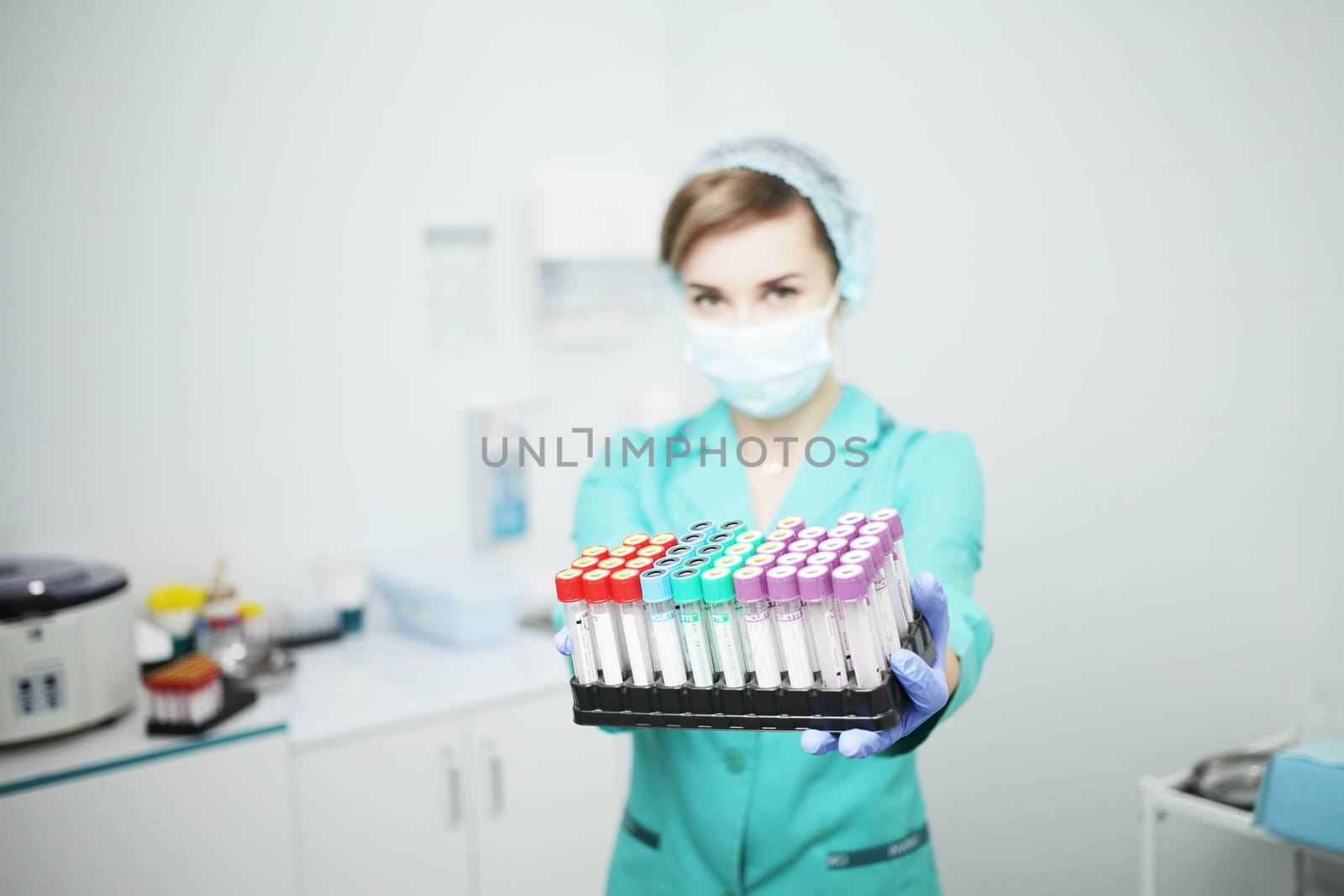 A woman nurse doctor in a medical mask holds test tubes for a blood test in her hands