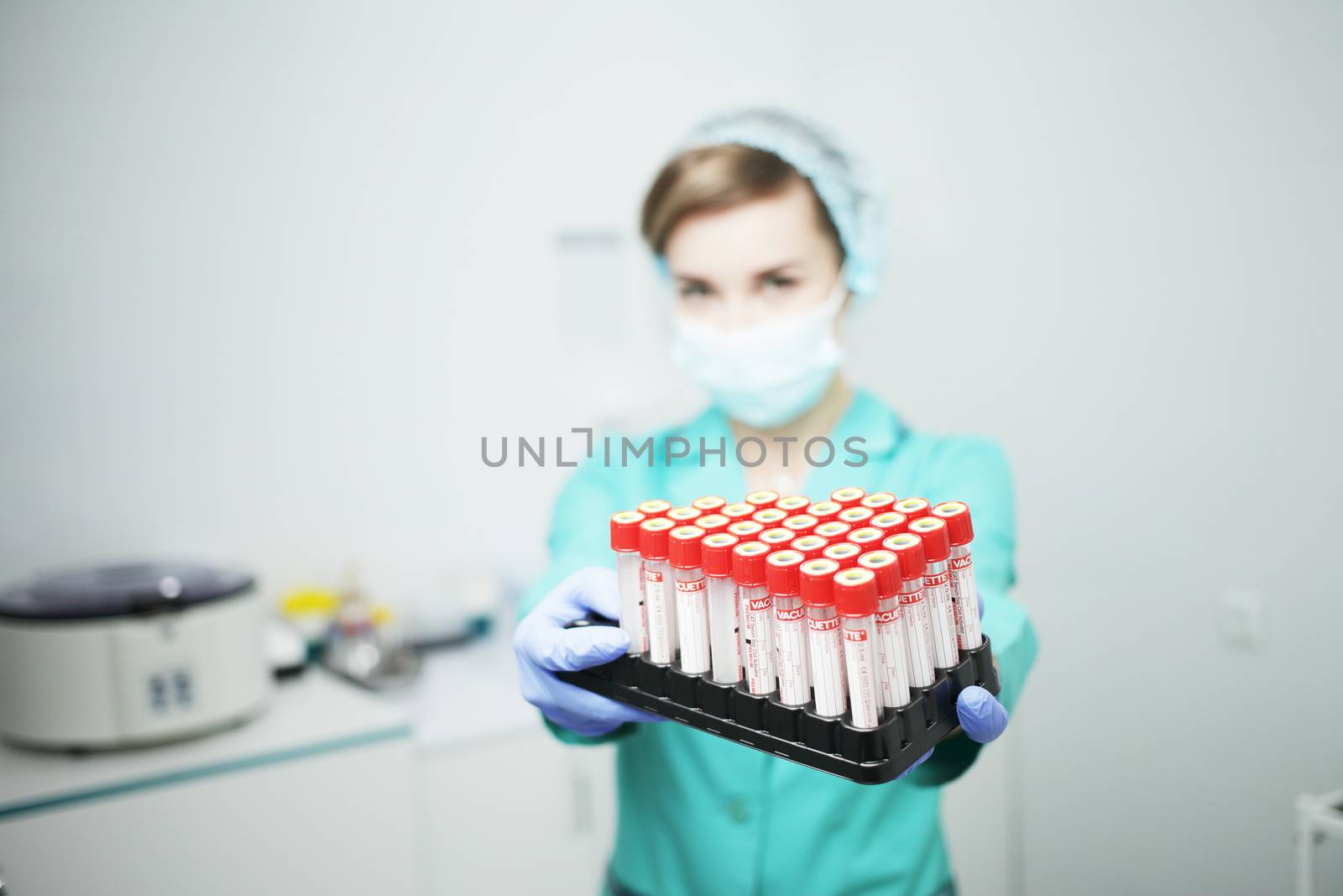 A woman nurse doctor in a medical mask holds test tubes for a blood test in her hands