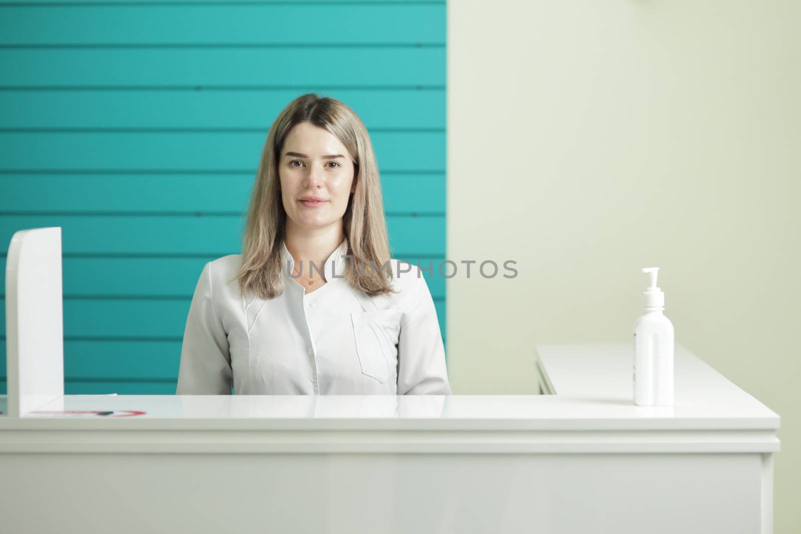 Female doctor or nurse in medical uniform. In the hospital reception. Disinfectant on the table