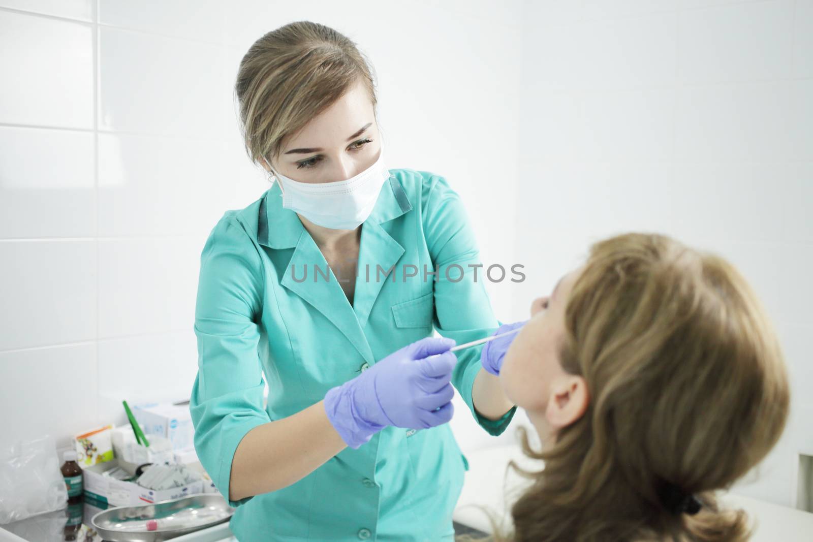 A nurse wearing a medical mask takes a swab from a patient's nose. by selinsmo