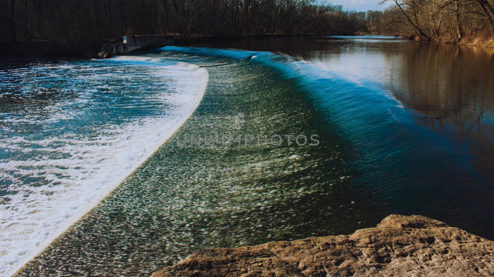 Fast Flowing Water Crashing Over a Man-Made Dam in a Dead Winter Forest