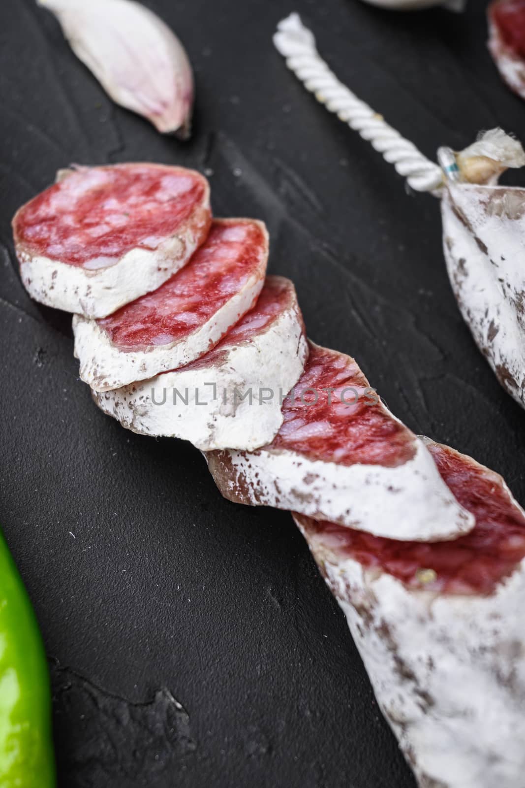 Dry cured fuet salami sausage slices on balck background.