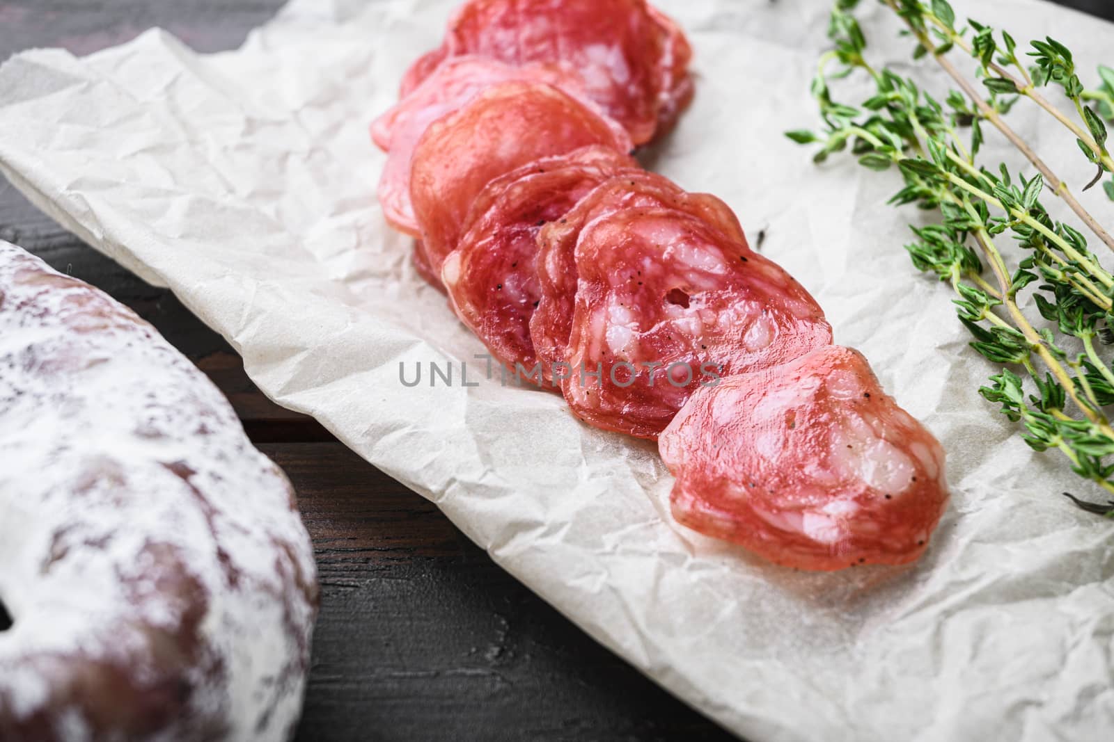Fuet, dry cured sausage cut to slices on old wooden table.