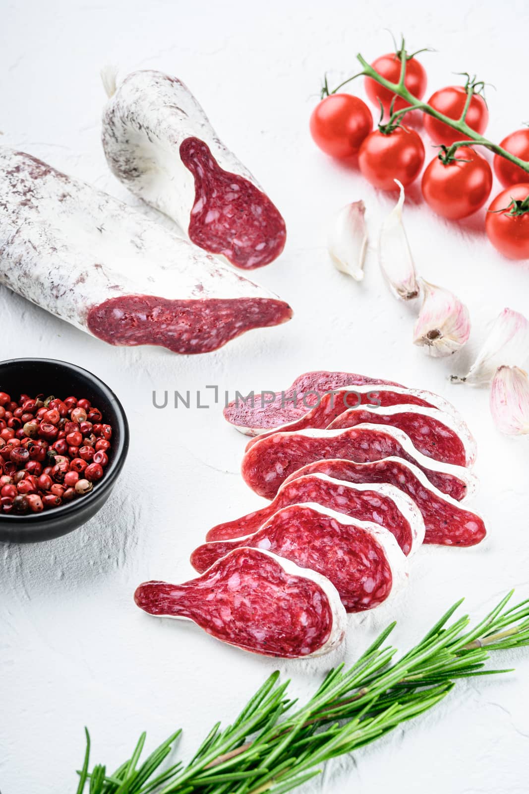 Sliced cuts of longaniza, dry cured spanish sausage with herbs and spices on white surface.