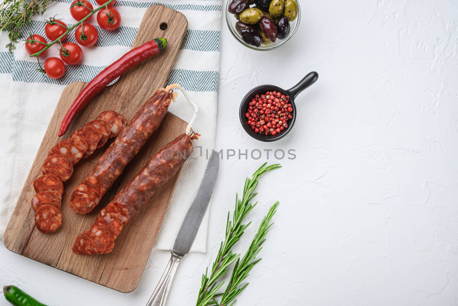 Traditional chorizo cuts with spices and ingredients on white textured background with space for text.