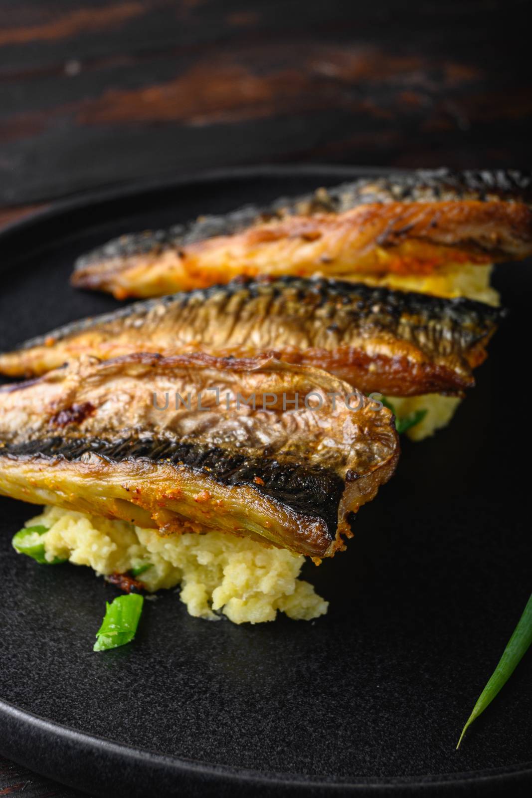 Dish of marinated mackerel with garlic paprika and saffron.with softly mashed potatoes on dark wooden table.