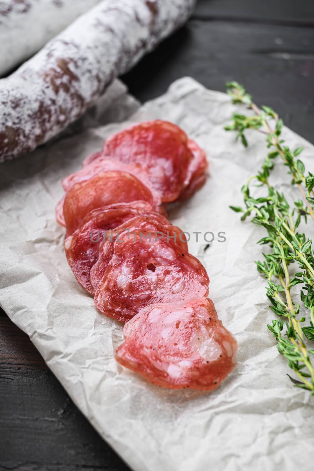 Fuet, dry cured sausage cut to slices on old wooden table.