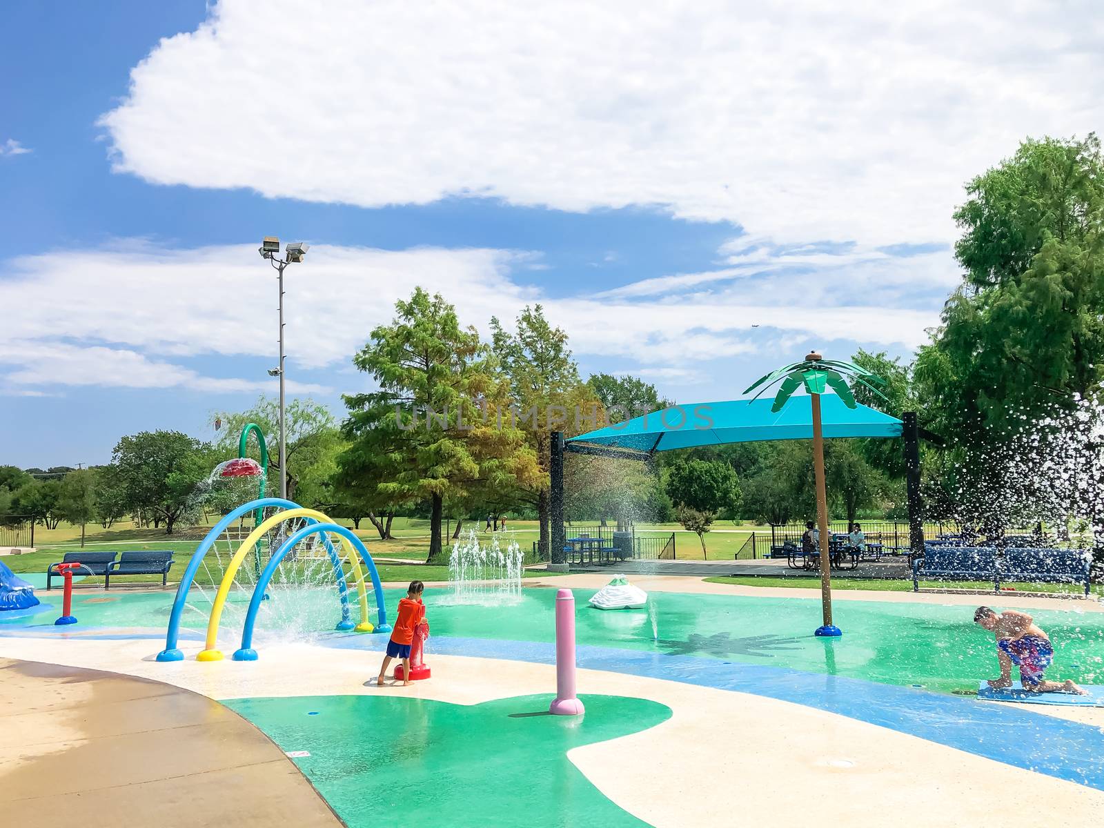 Diverse kids playing at splash pad water fountains near Dallas, Texas, America in summertime by trongnguyen