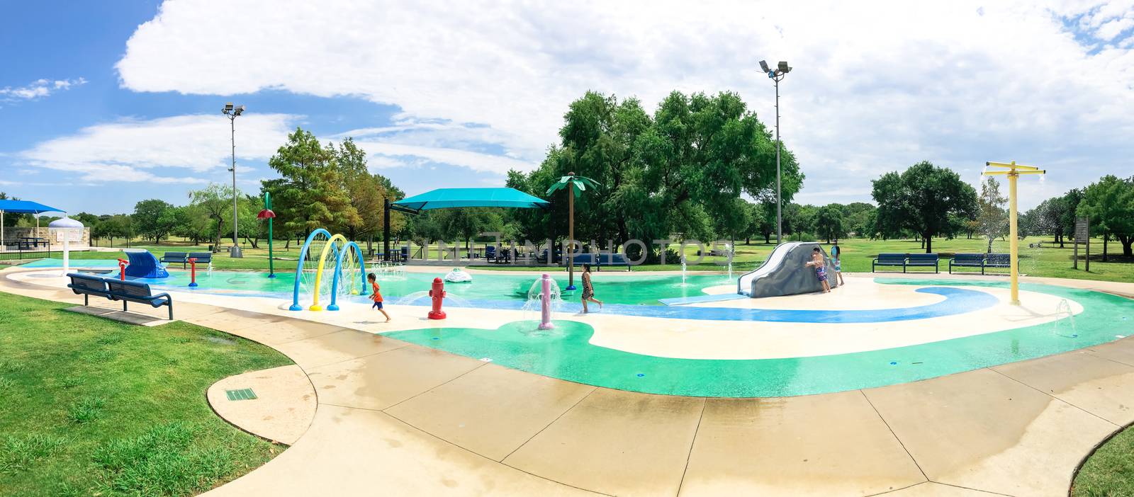 Panoramic colorful splash pad water playground with Asian toddler boy playing near Dallas, Texas, America by trongnguyen