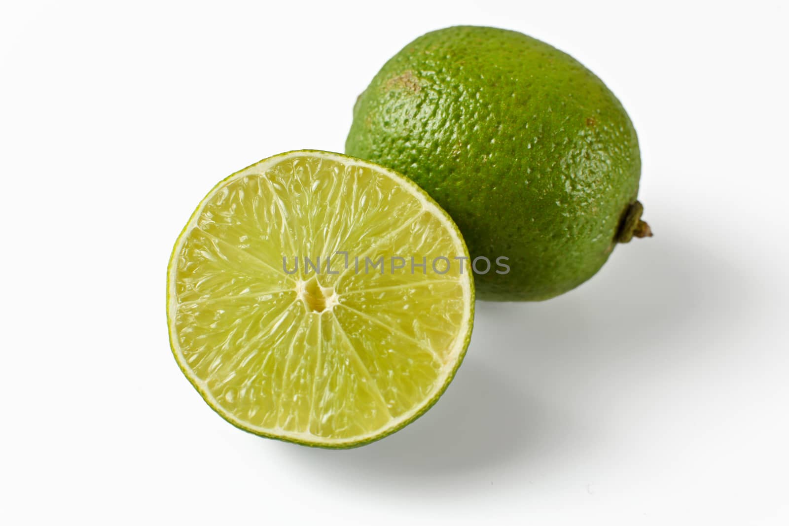 Whole lime and other one cut in half, isolated on white background.