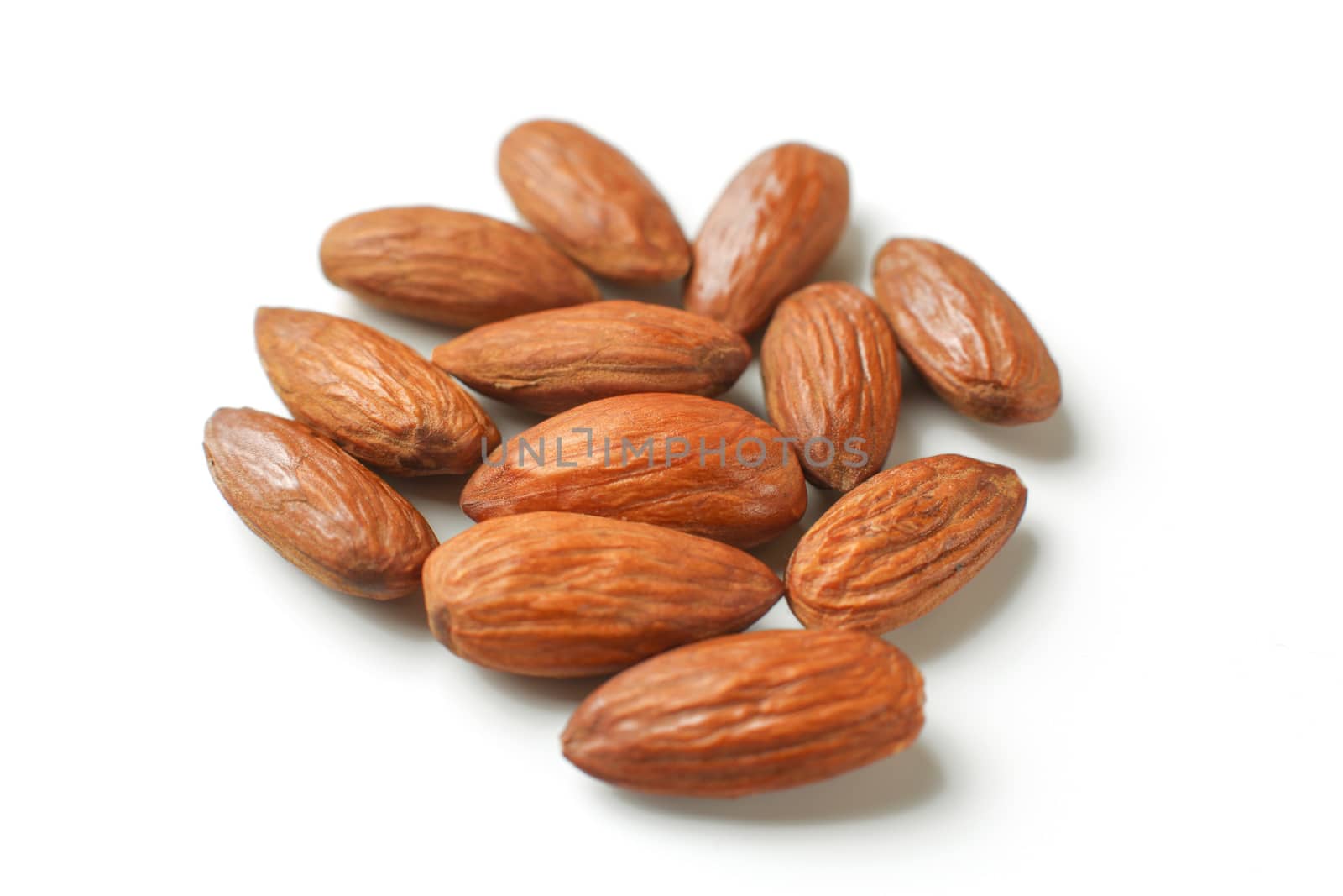 Pile of almond nuts isolated on white background. by Ivanko